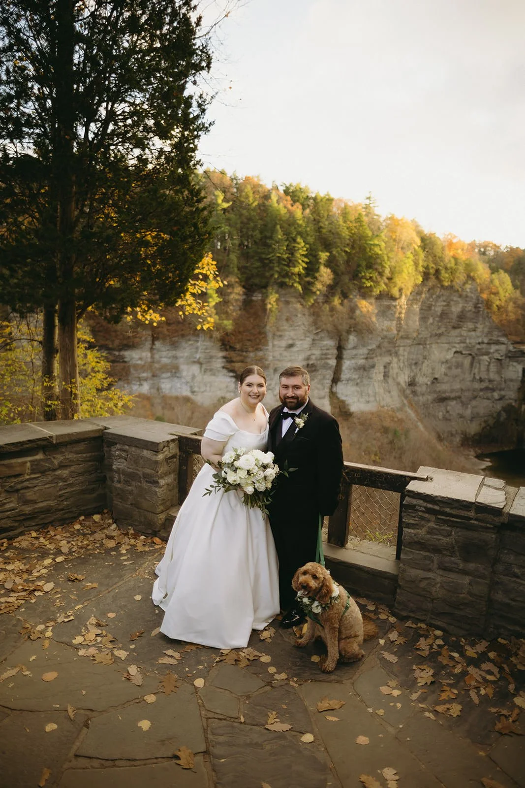 The bride and groom smile ear to ear as they pose with their furry friend.