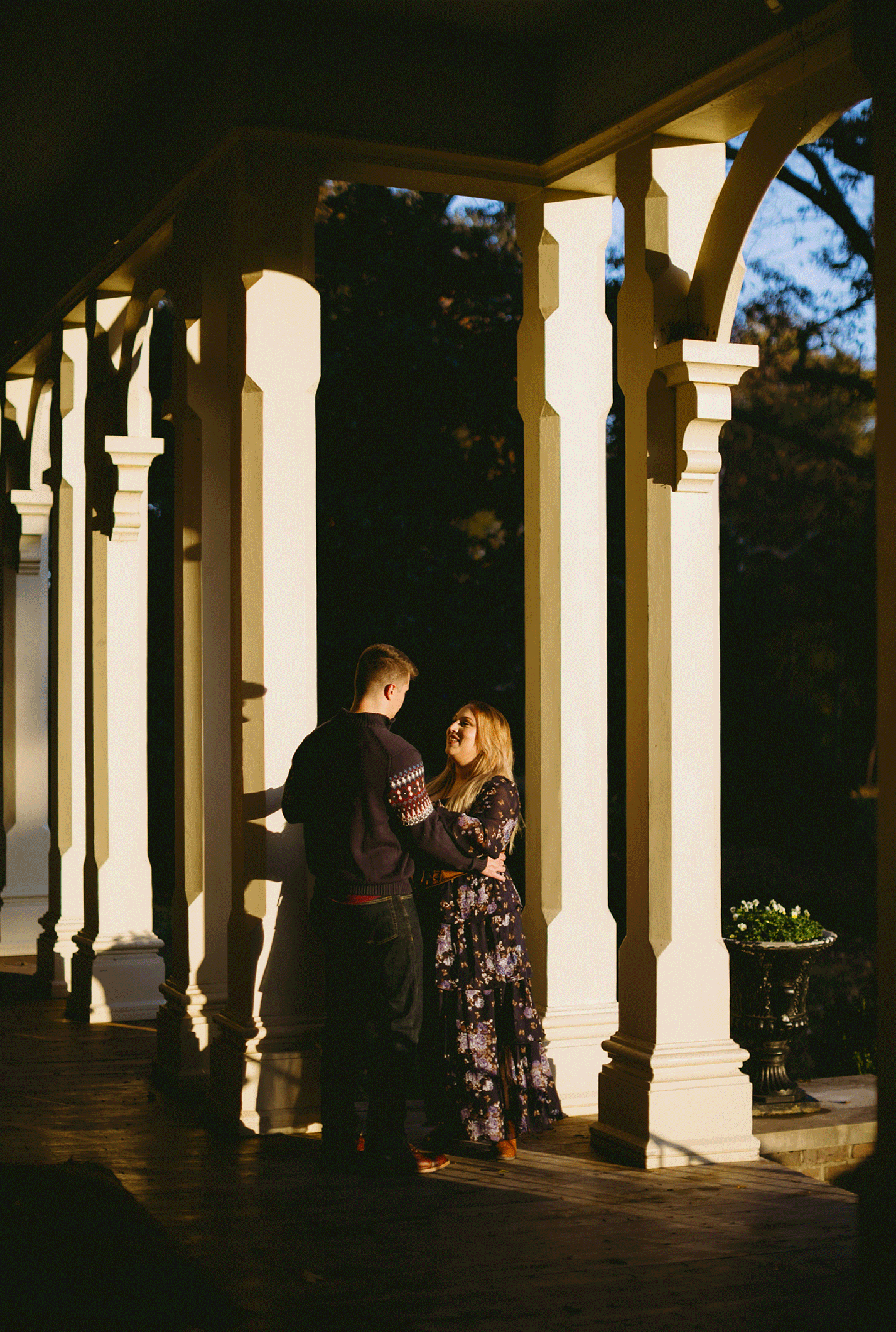 The couple stand on the deck of the historic building dancing together.