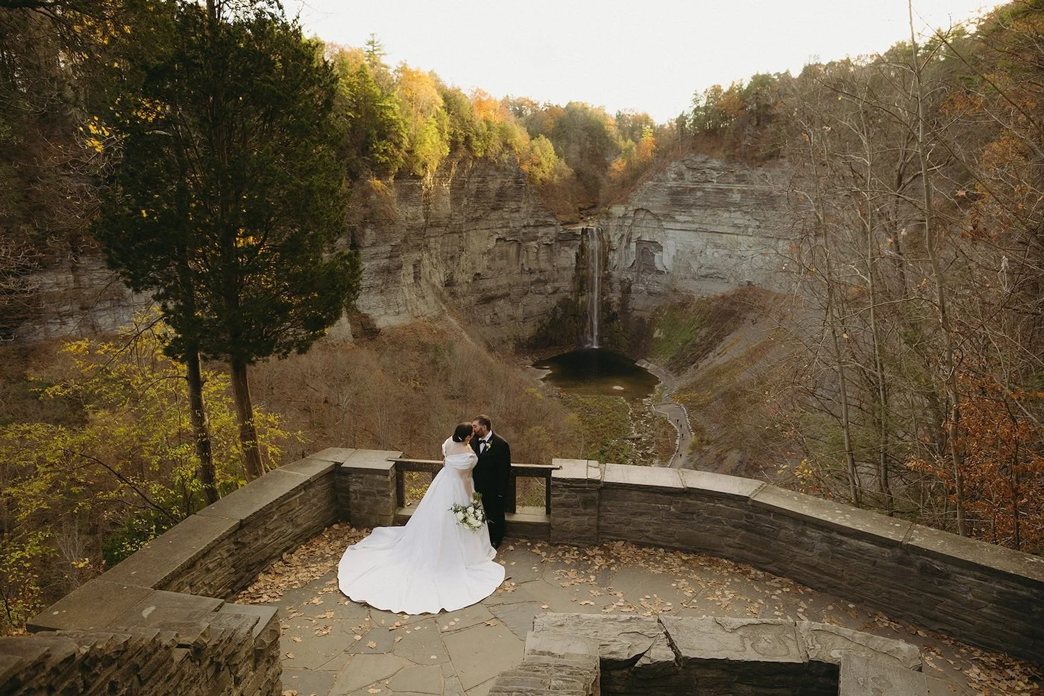 The bride and groom share a kiss with the falls as their background.