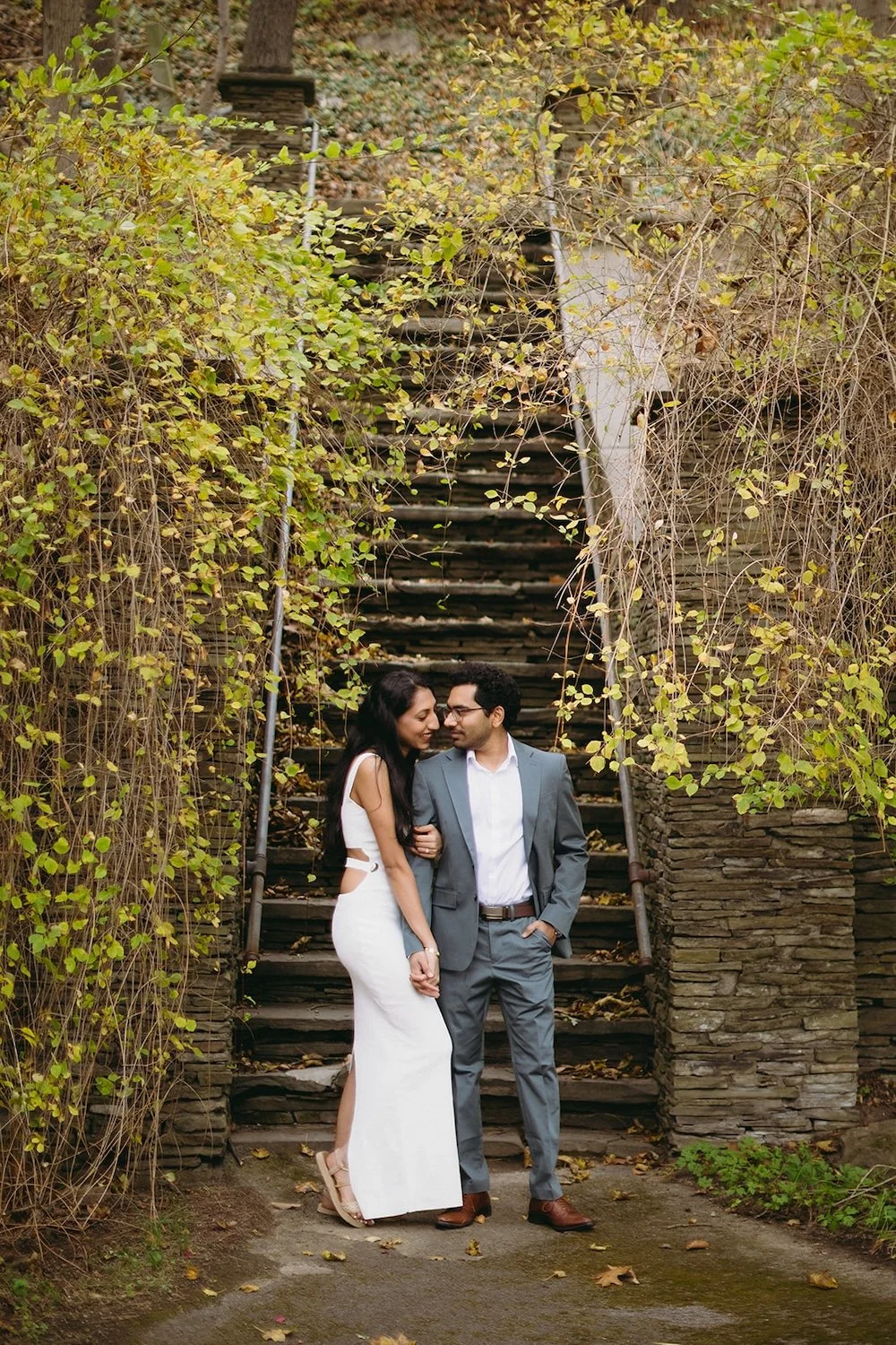The couple stand at the bottom of the steps as the future bride holds her groom close.