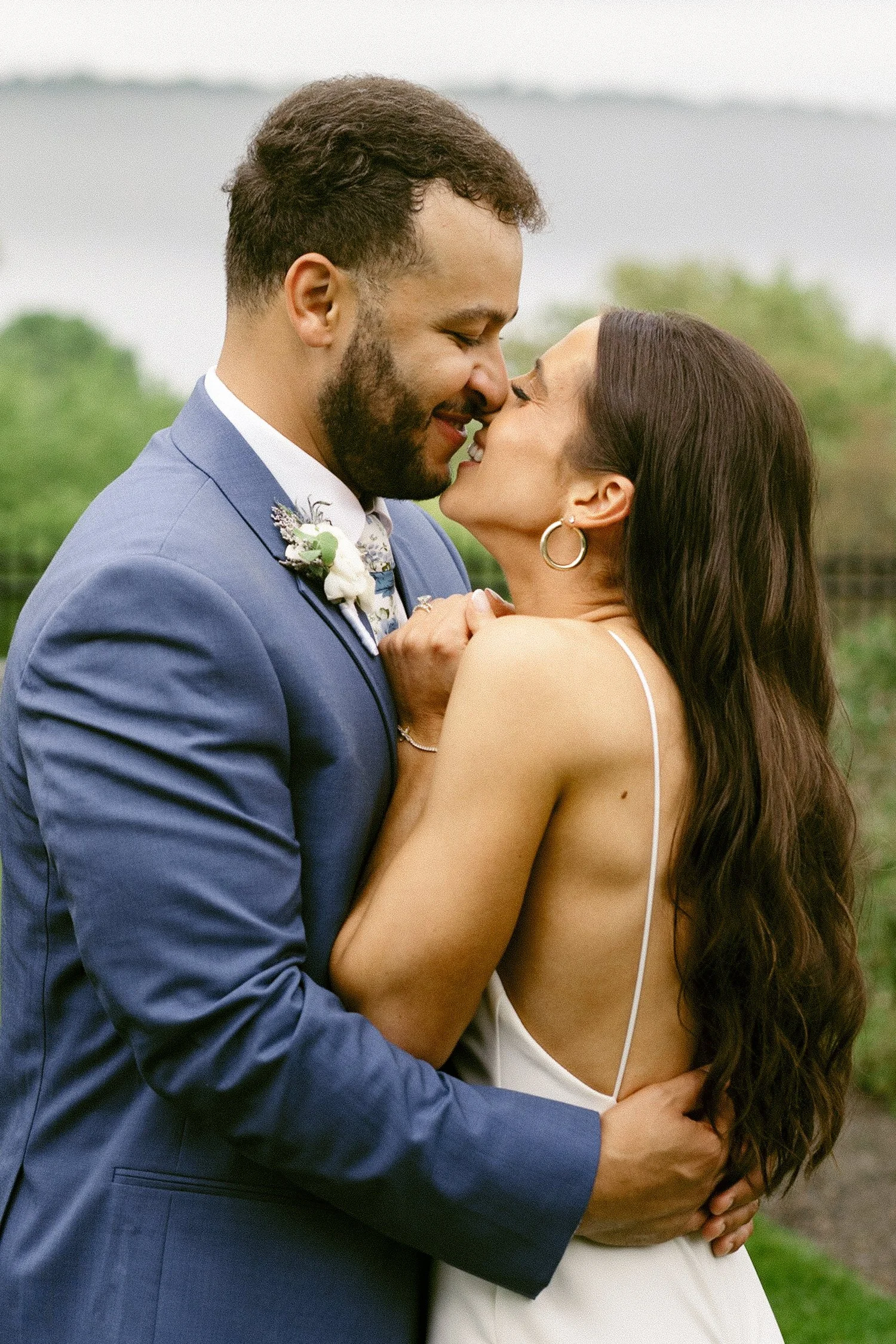 Intimate wedding portrait of a bride and groom sharing a soft kiss outdoors, natural and emotion-rich wedding photography.