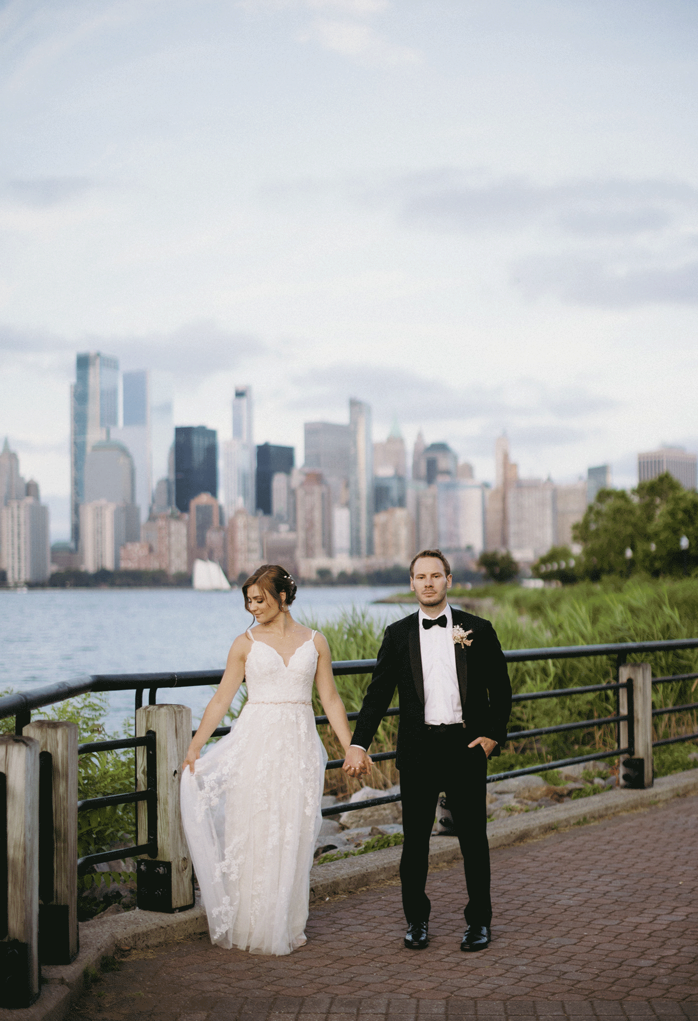 GIF photo of the bride fanning her gown while on the brick pathway. The river and city as their background.