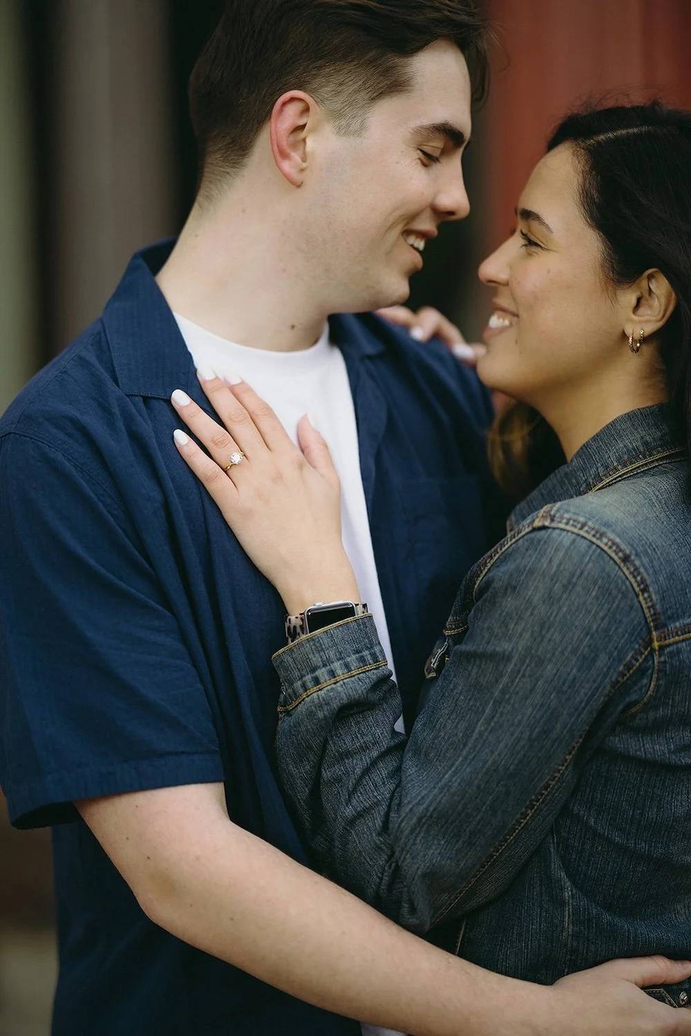 The couple hold one another close looking into each others eyes with a settle view of the engagement ring.