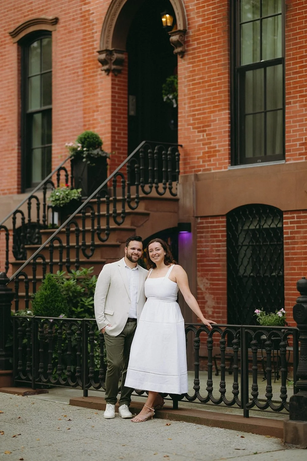 Couple rests on a railing of a brown stone.
