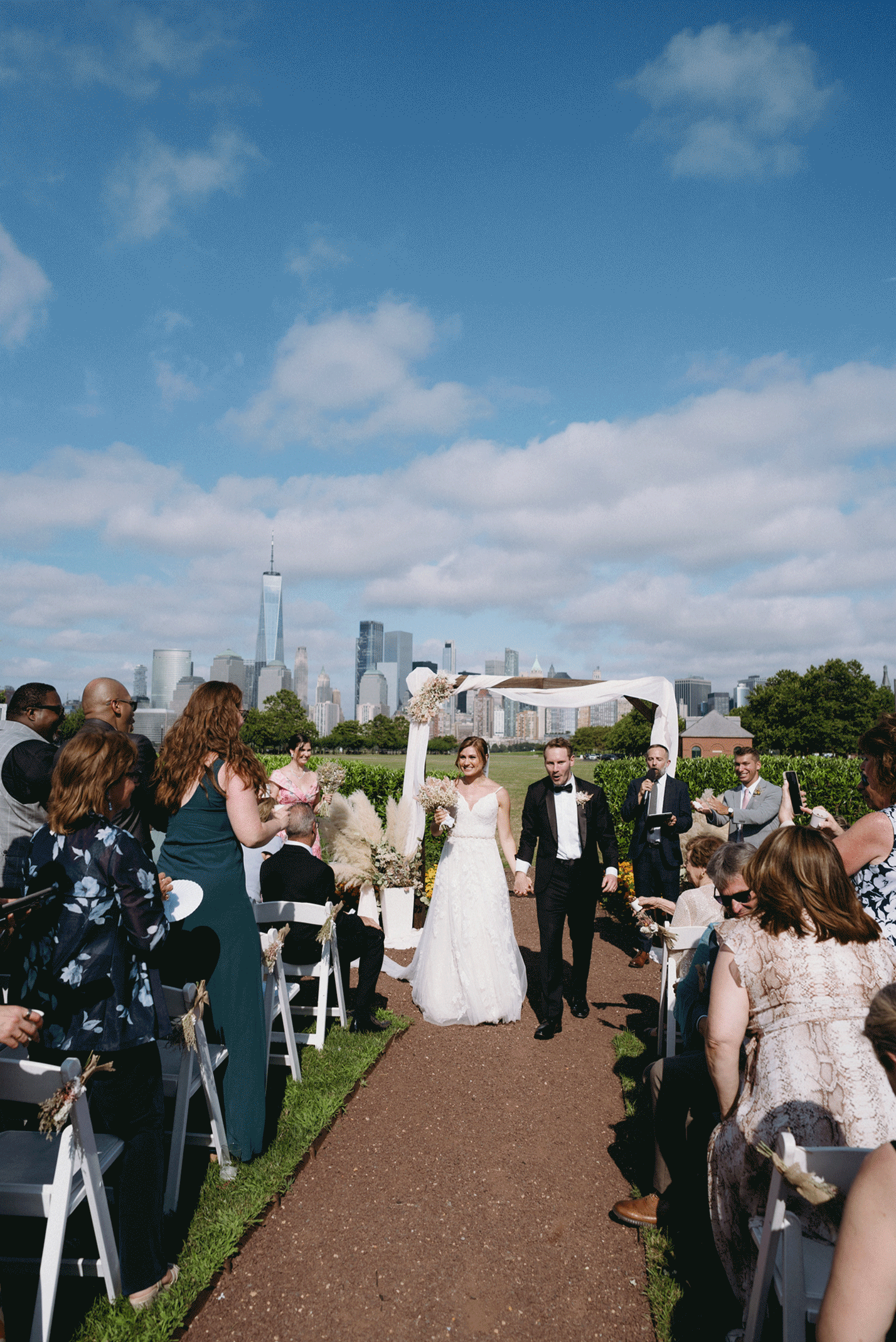 GIF photo of the bride and groom walking the aisle as husband and wife. Family and friends celebrate with the floral toss.
