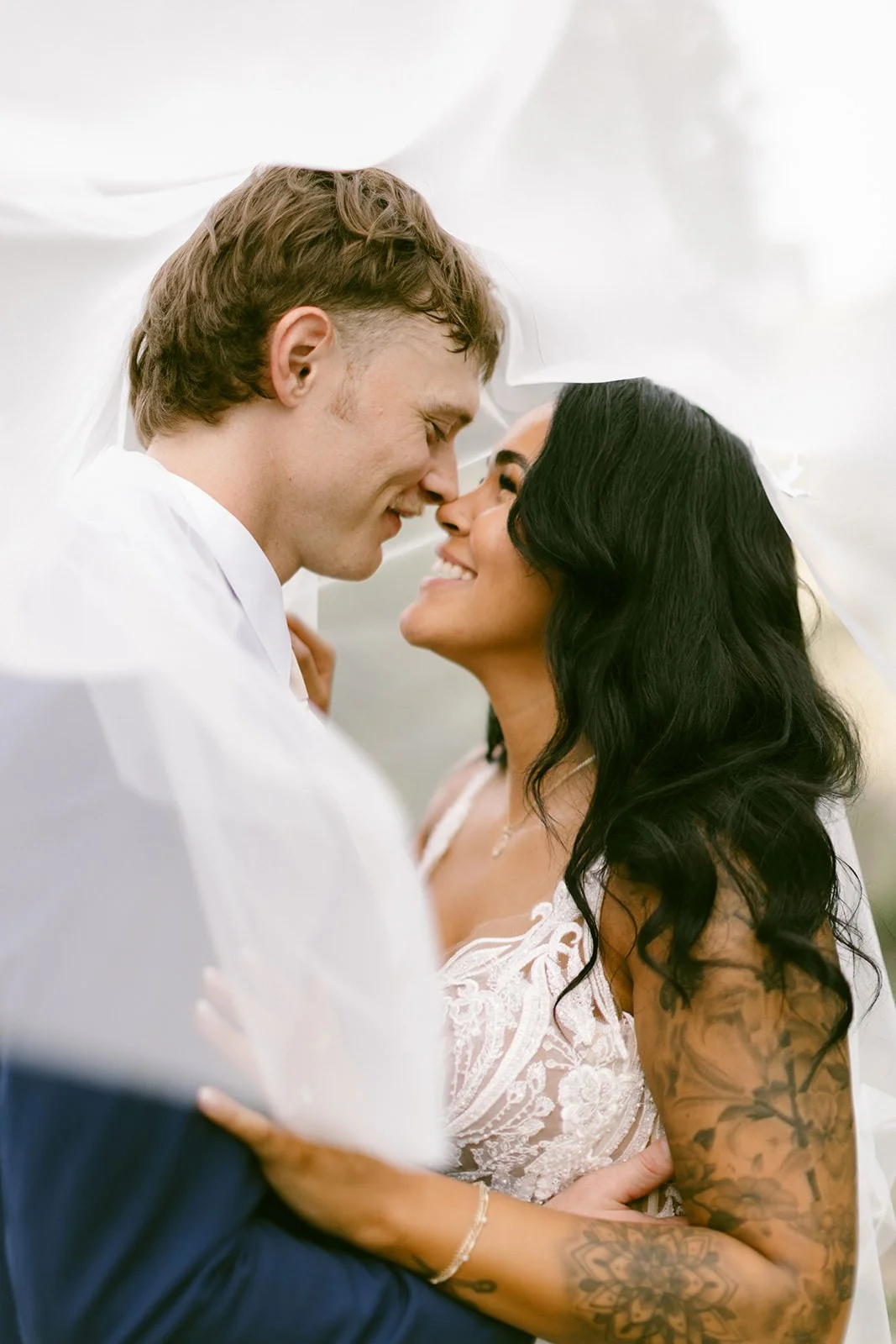 Intimate close-up wedding photo of a bride and groom sharing a quiet moment under a veil, soft and romantic wedding imagery.
