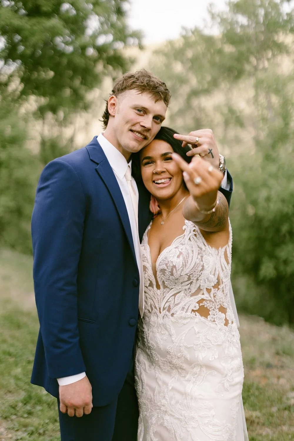 The bride and groom pose together as they show off their wedding bands.