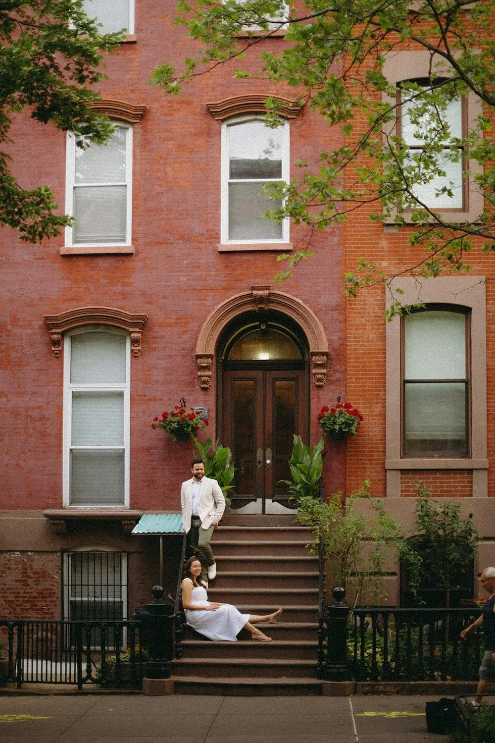 Couple relax on the stairs of a brownstone building.