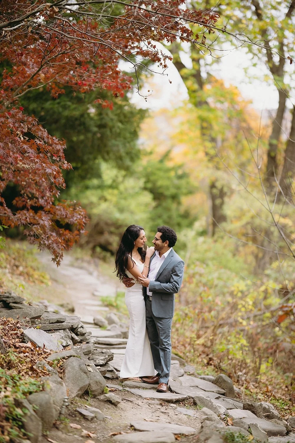 The couple stands close together as they share a smile together.