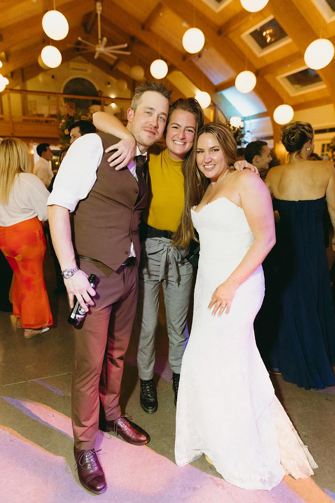 Wedding photographer celebrating on the dance floor with a bride and groom at a lively reception, fun and candid wedding photography.