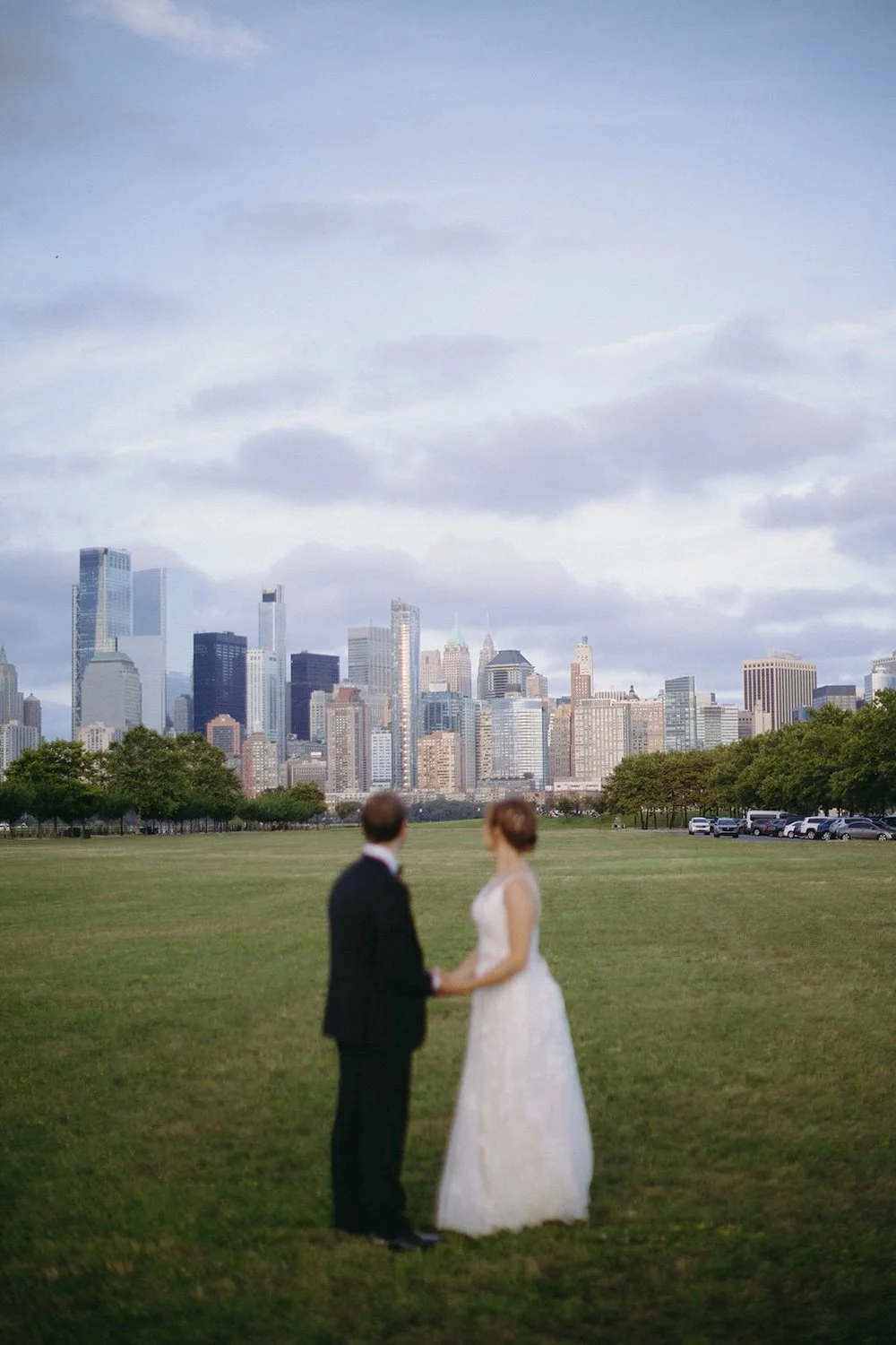 The wedding couple stand hand-in-hand as they admire the view of the city.