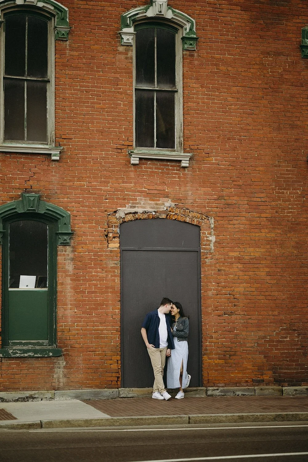 The couple lean against building as they hold one another closely.