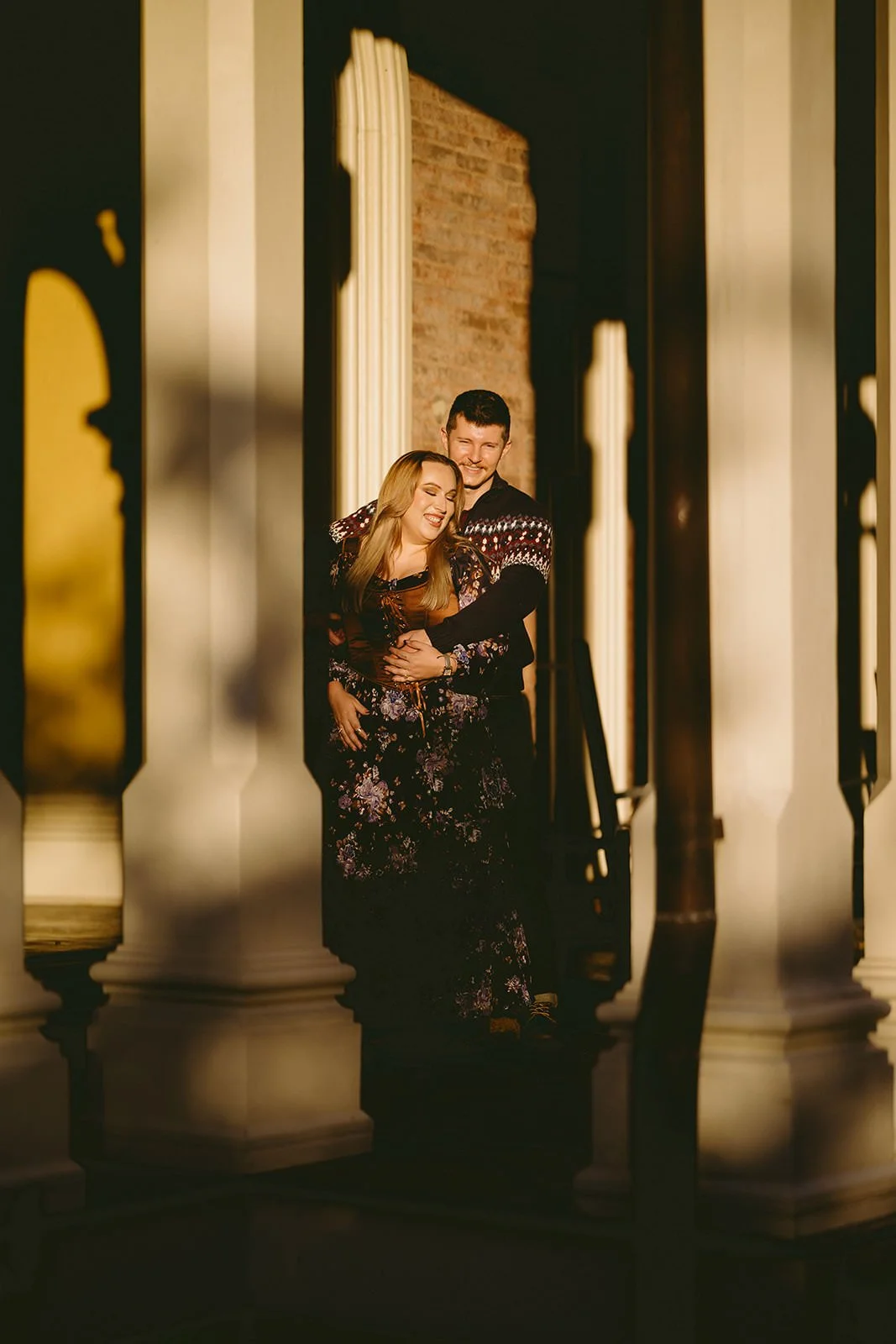 The future groom wraps his arms around his bride to be as they smile.