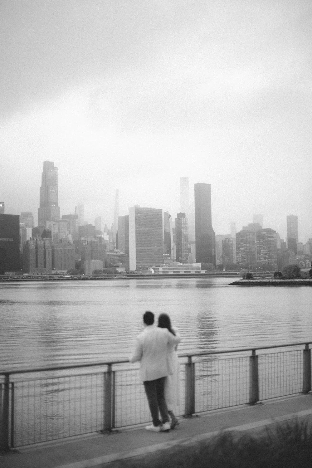 Black and white photo of the couple admiring the view of the city from the walking path.