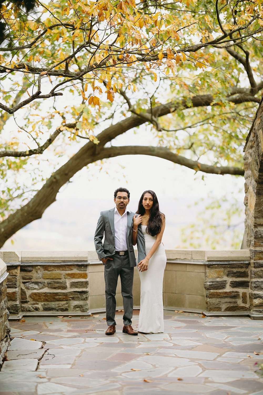 The couple stand side by side on the patio of the church the future bride holds her groom close.