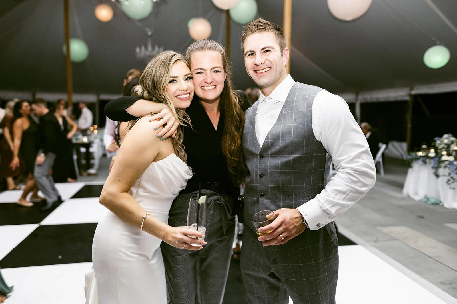 Wedding photographer posing with smiling bride and groom on dance floor.