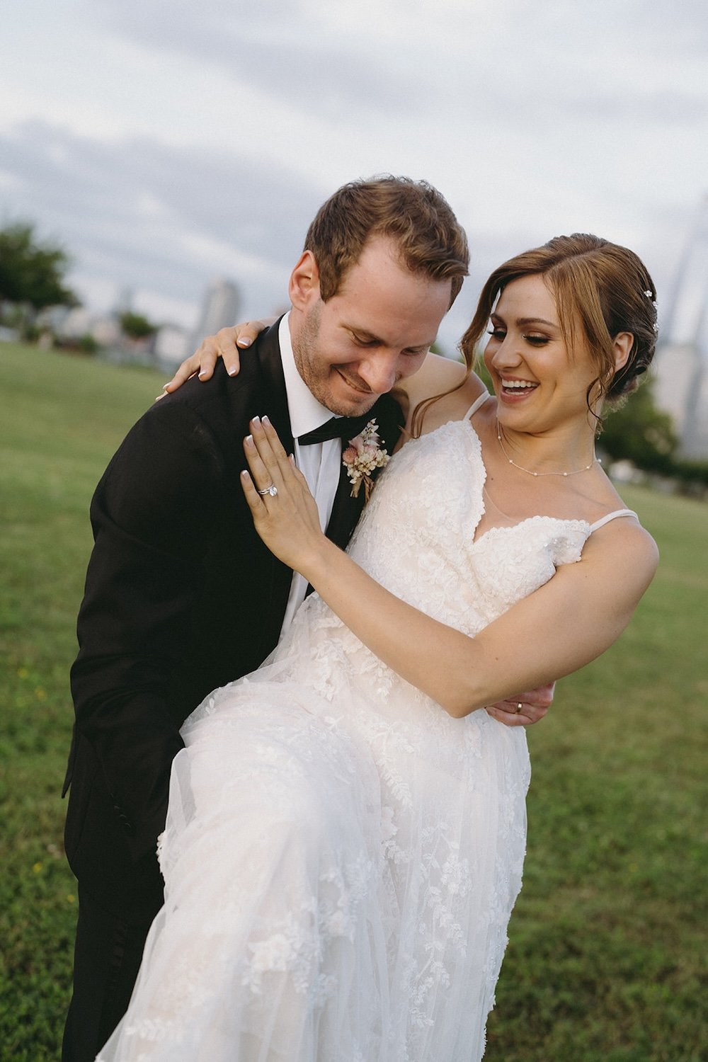 The groom picks up his bride as they're both smiling.