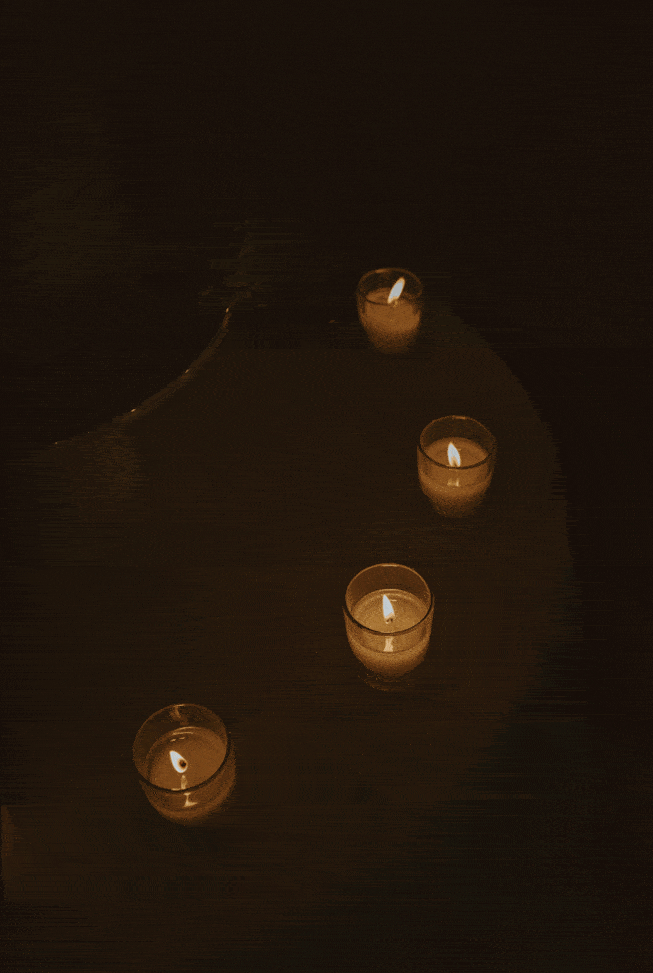 Four small votive candles glowing in dark intimate setting.