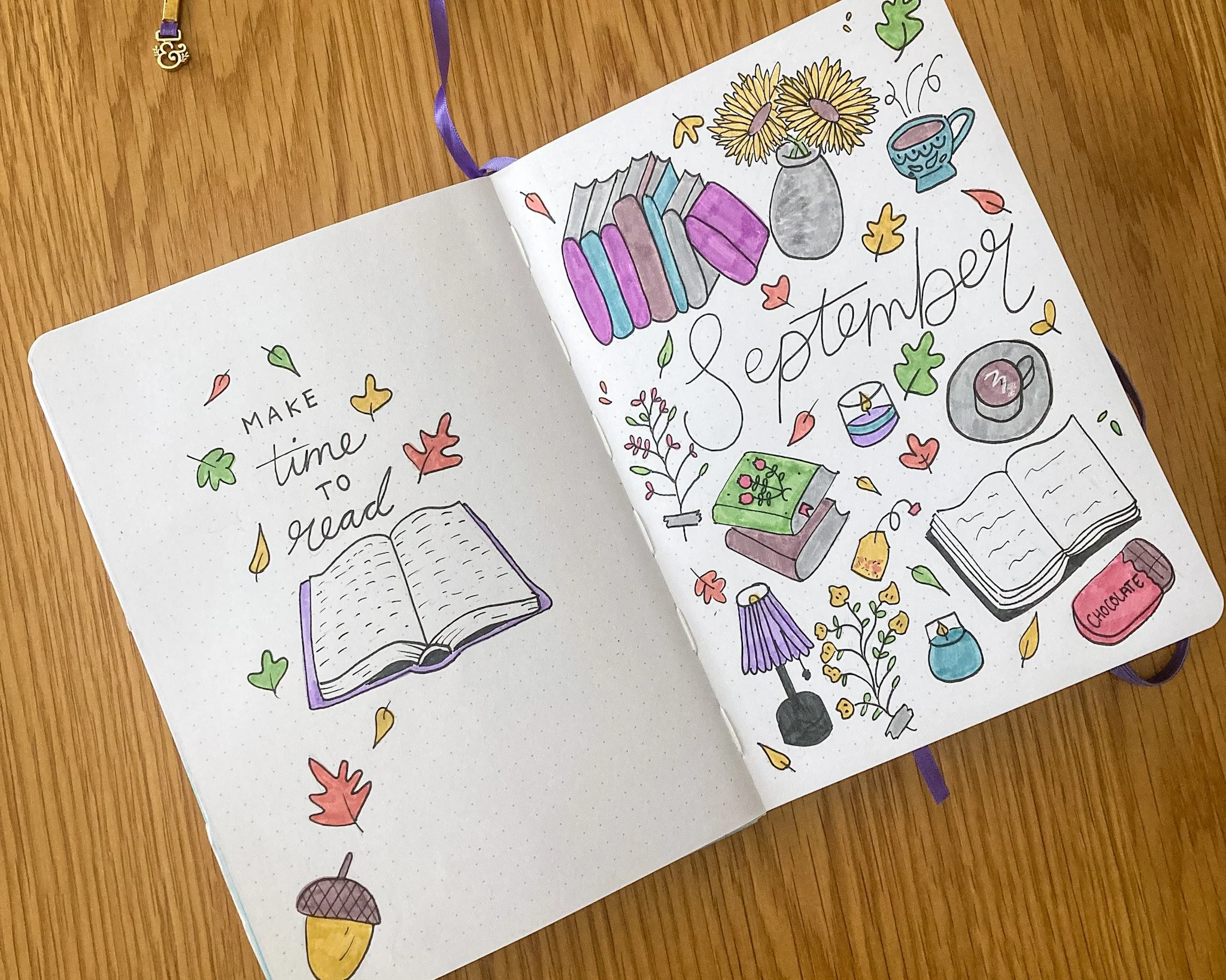 An open notebook displaying a drawing that depicts books and autumn leaves. The word "September" is written in the centre.