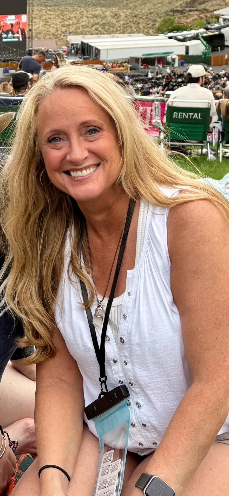 A black and white portrait of a woman with wavy blonde hair, wearing a black turtleneck, smiling slightly, looking at the camera.