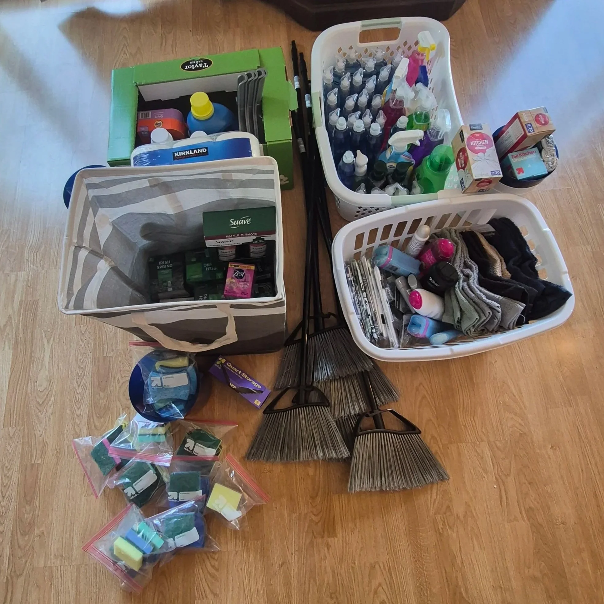 Collection of donated household essentials, including cleaning supplies, toiletries, towels, brooms, and kitchen items, gathered by Onward residents, board members, and volunteers to help people moving into housing after experiencing homelessness.