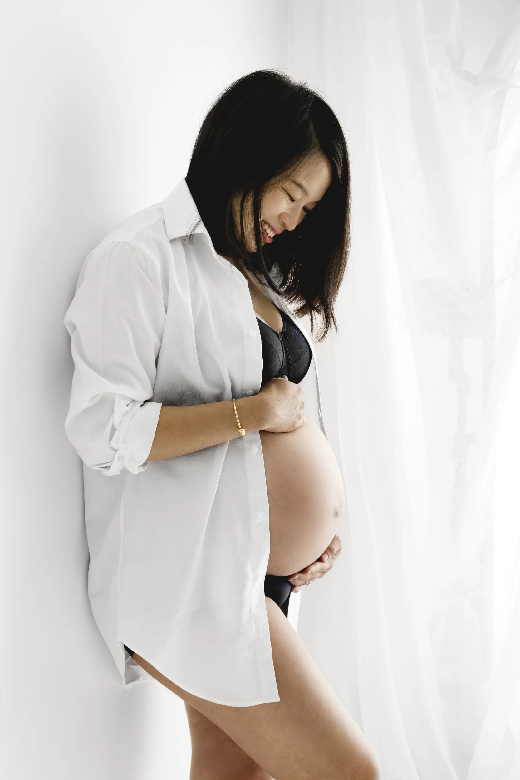 Pregnant woman looking at her bump during natural maternity photoshoot at Dundee studio