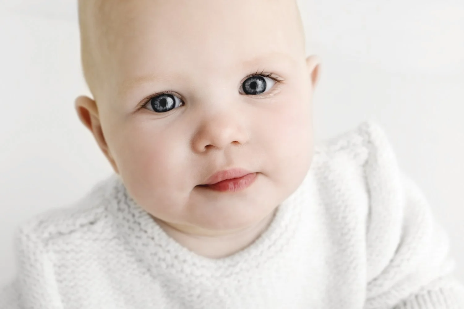 9 month old baby sitting and looking off camera during baby photoshoot in Dundee