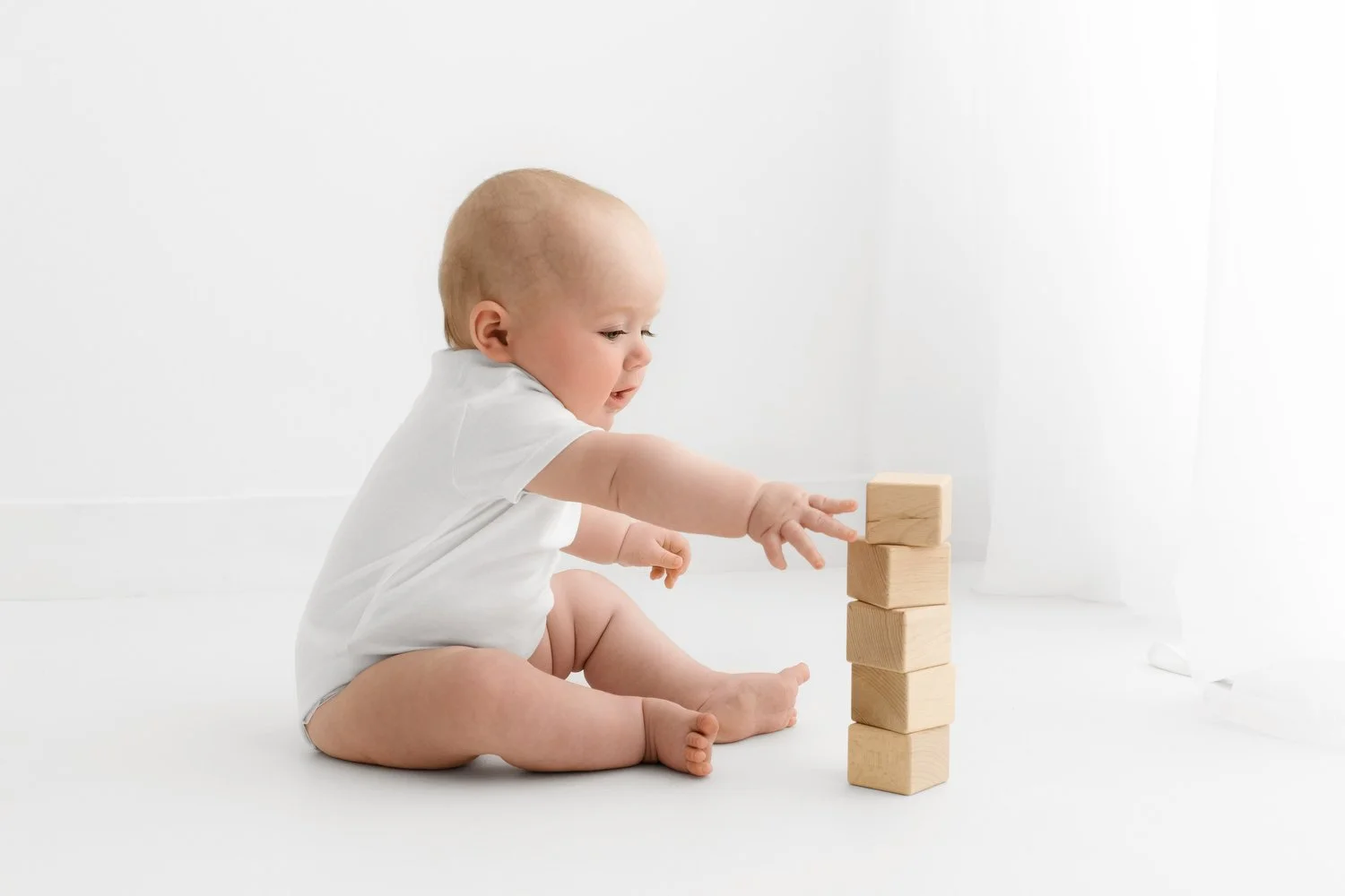 6 month old baby playing naturally with wooden bricks at photoshoot at Mabel and Moose studio Dundee