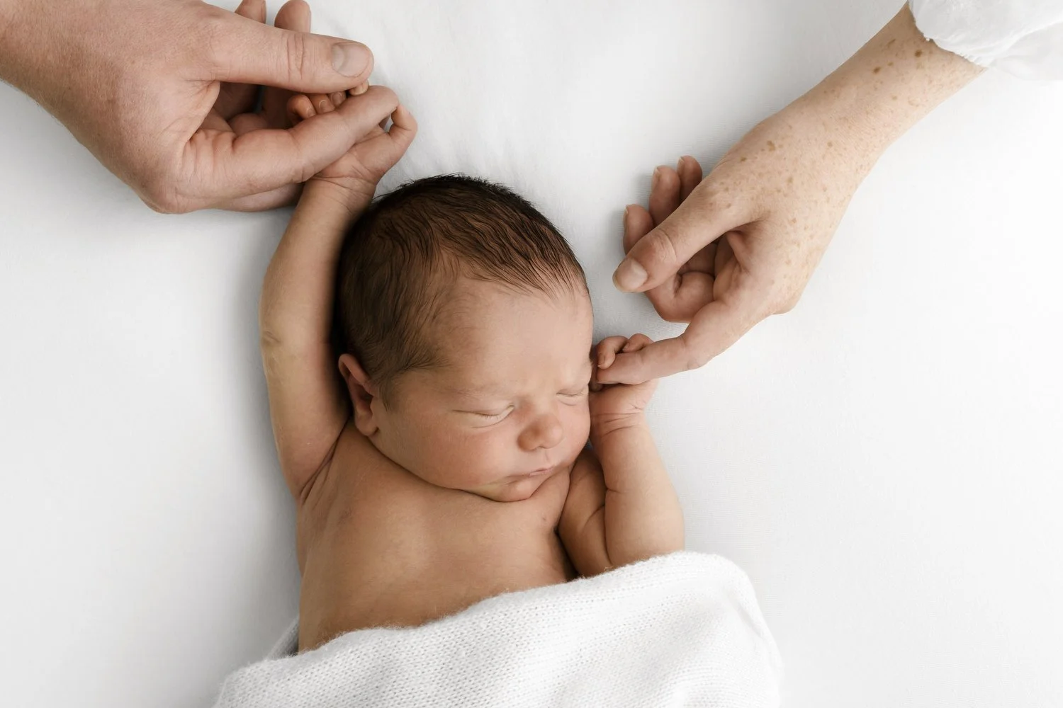 Mum and dad's hands gently holding their newborn baby's fingers at Mabel & Møøse Dundee