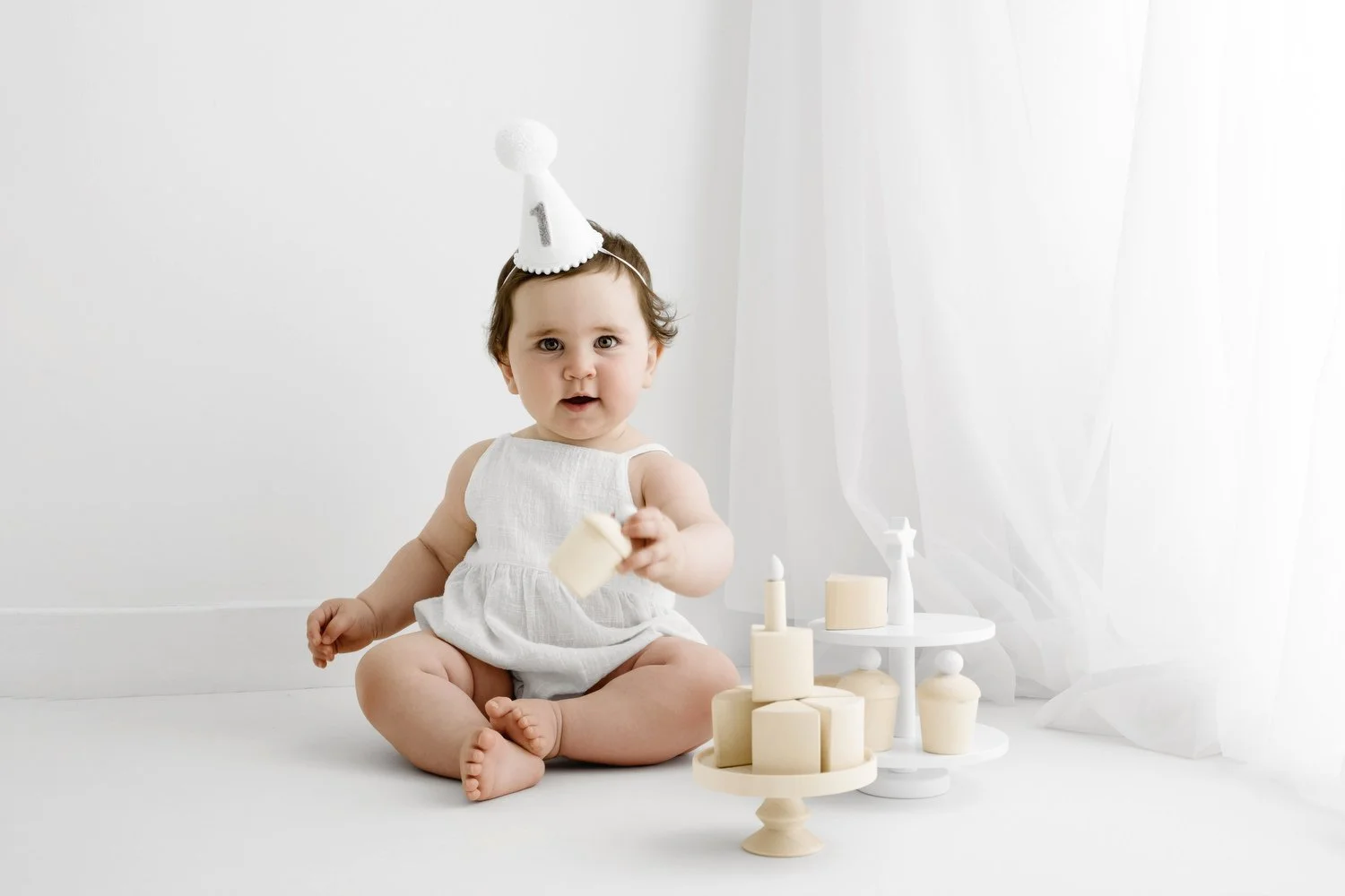 12 month old baby girl with wooden birthday cake at Dundee first birthday photoshoot