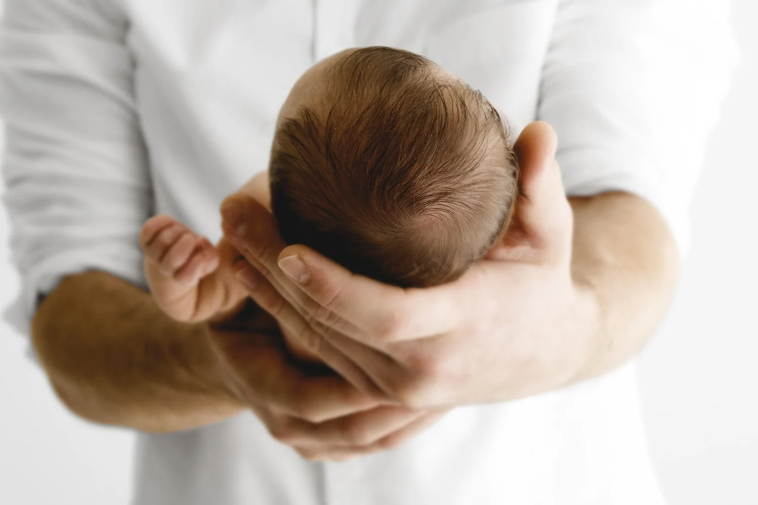 Newborn baby head cradled in dad's hands at Mabel and Moose studio Dundee