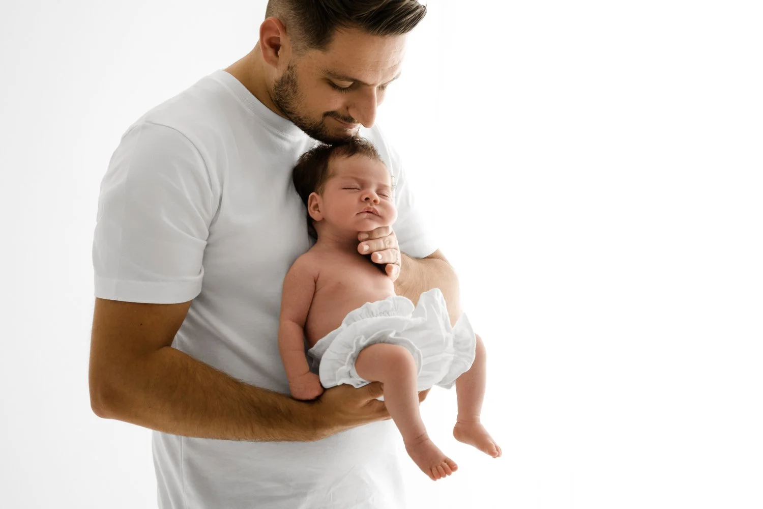 Dad holding newborn, illustrating a luxury, welcoming newborn photography experience