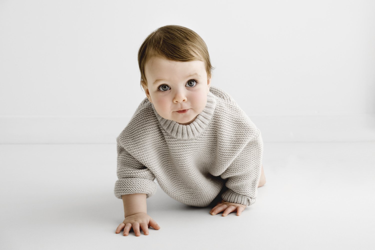 9 month old baby crawling wearing neutral knitted jumper