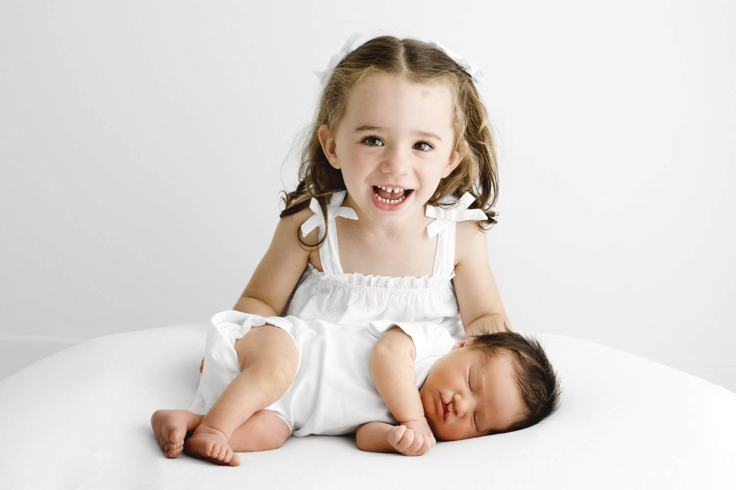 Toddler gently looking at newborn sibling during natural family photoshoot in Dundee studio