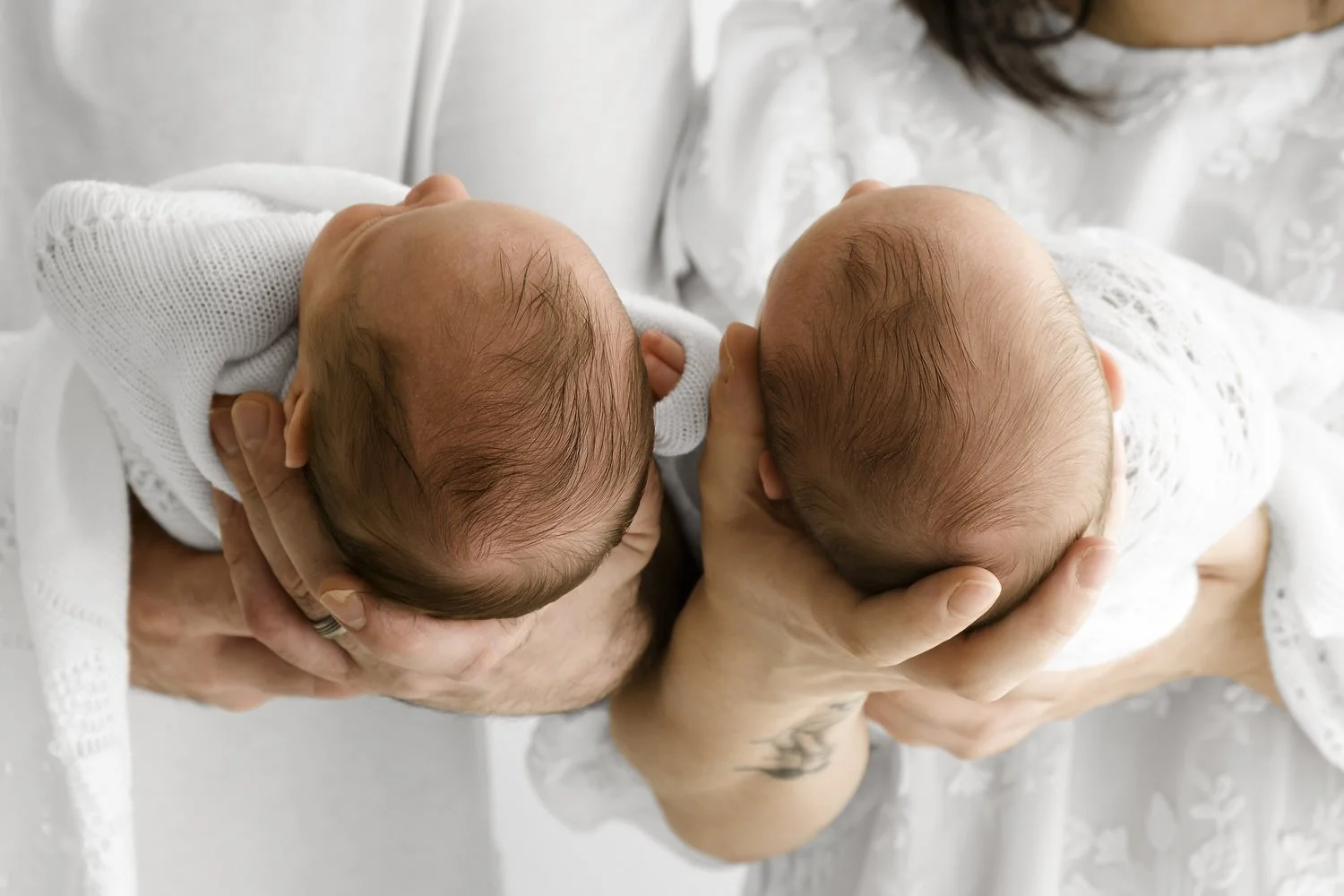 Twin newborn babies heads held by parents at Mabel and Moose studio Dundee