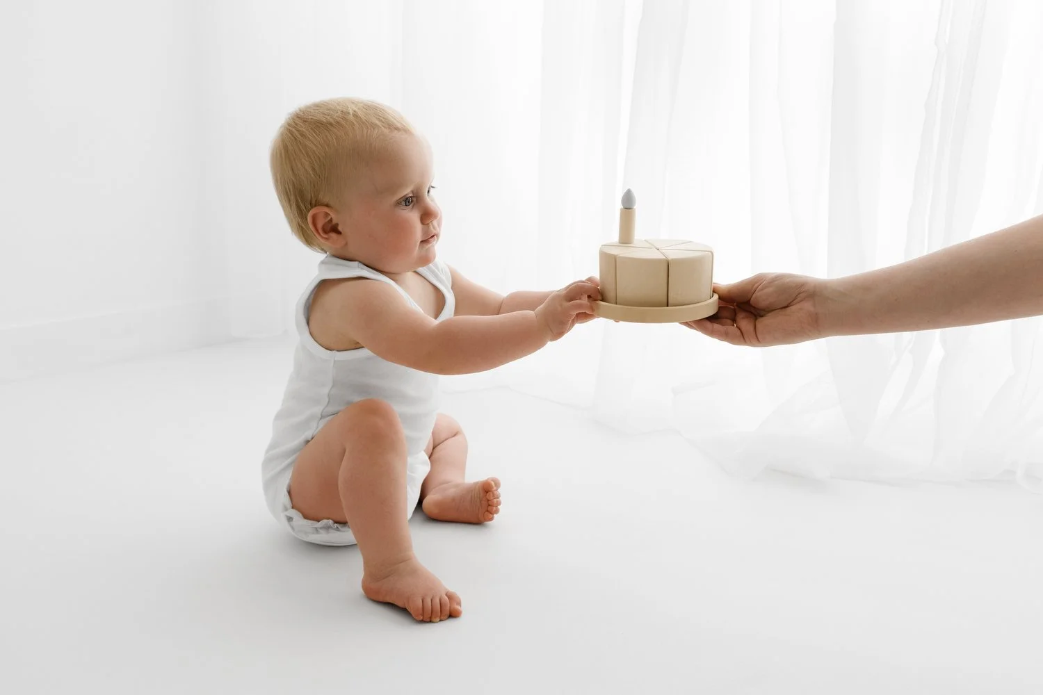 Baby reaching for a dinky wooden cake in a timeless birthday photography setup
