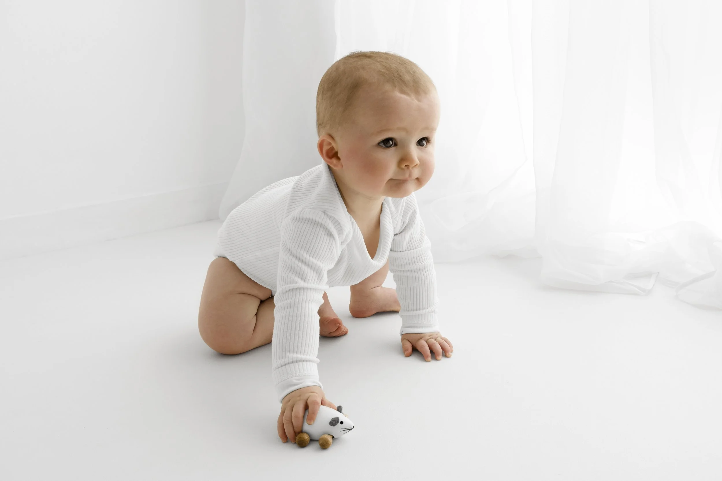 Crawling baby in white long-sleeved vest during Dundee studio photoshoot