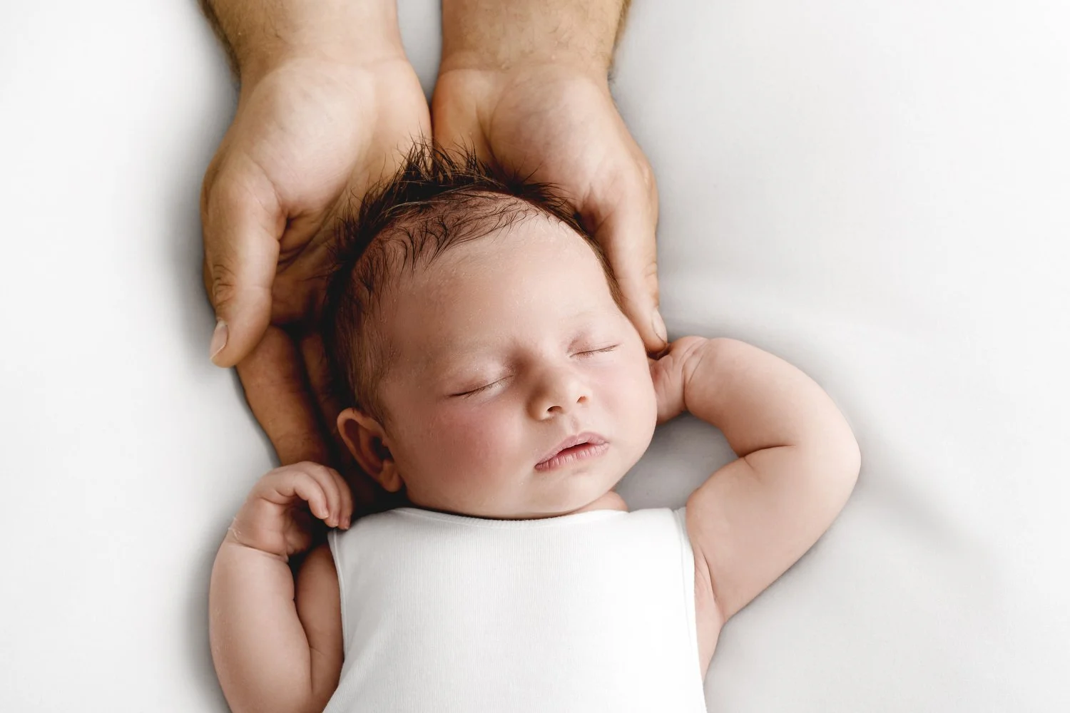 Close-up of parents hands holding their newborn baby in soft natural light