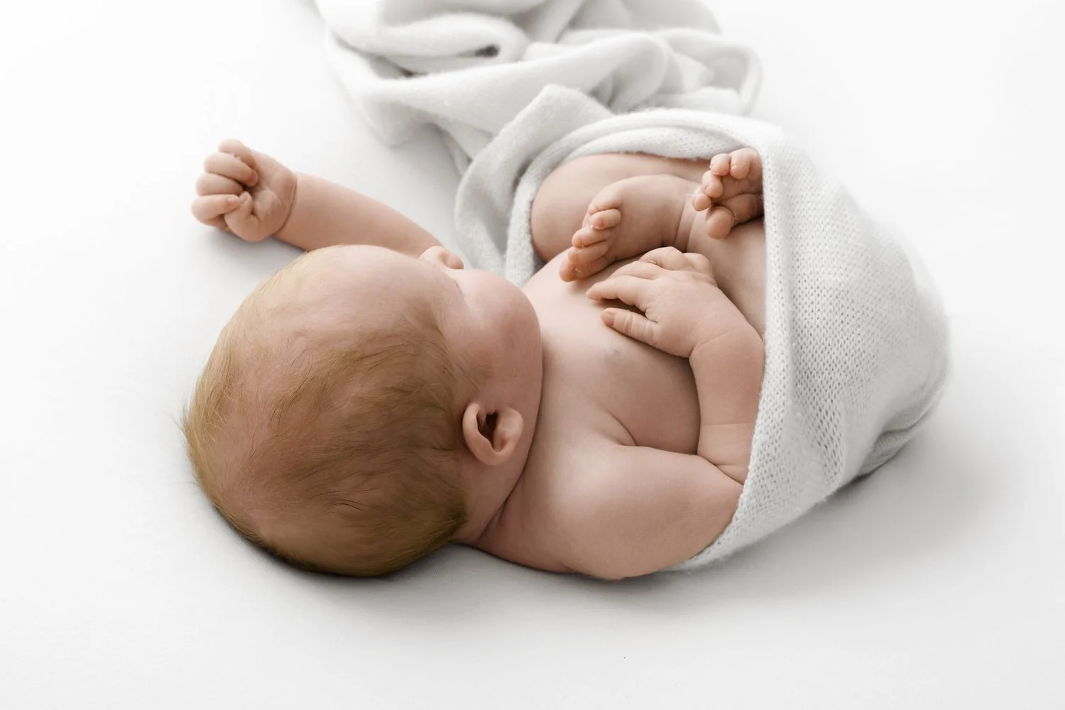 Newborn baby wrapped in white blanket at Mabel and Moose studio Dundee