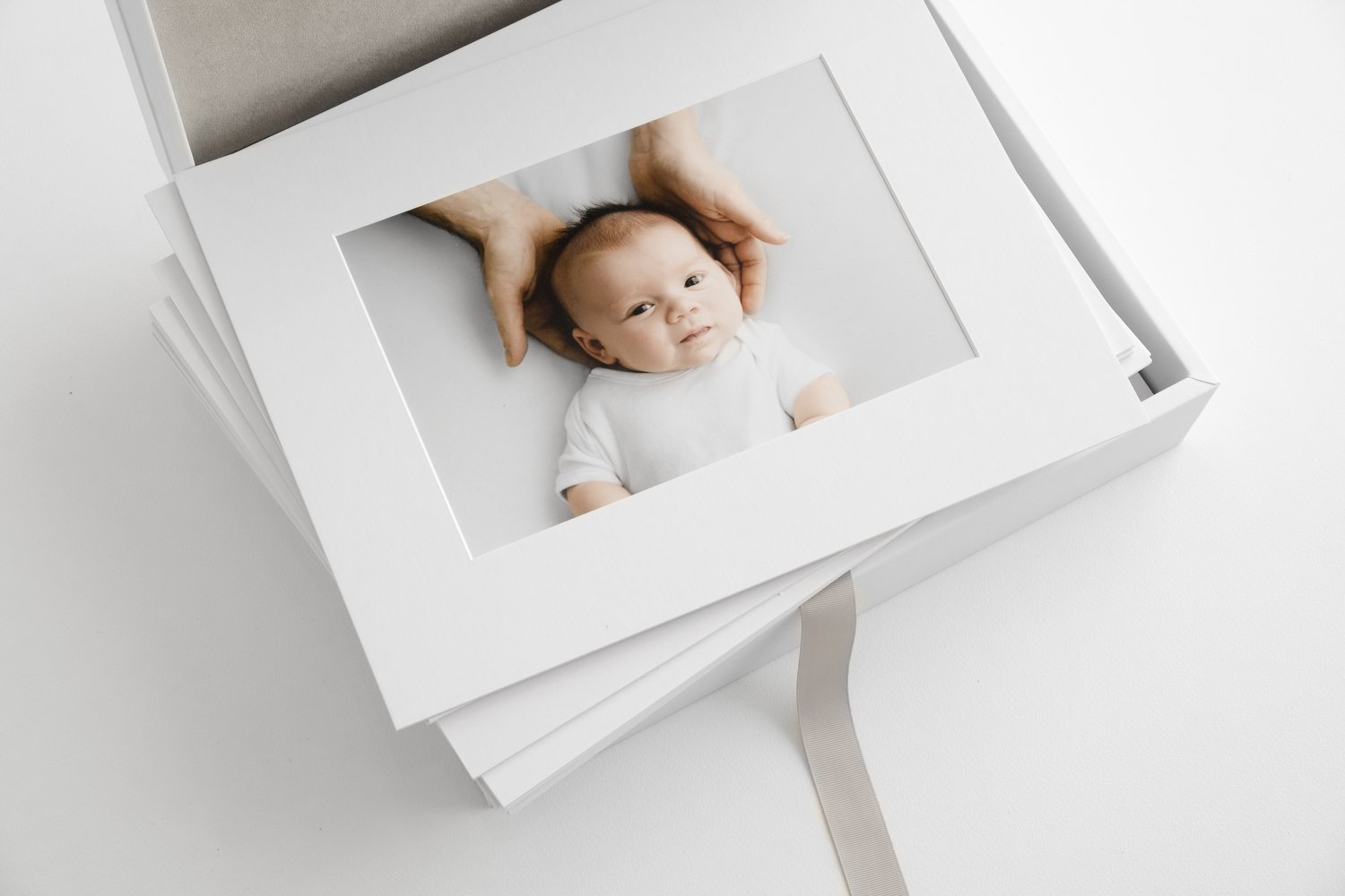 Mounted newborn photographs presented in white print collection box at Dundee studio