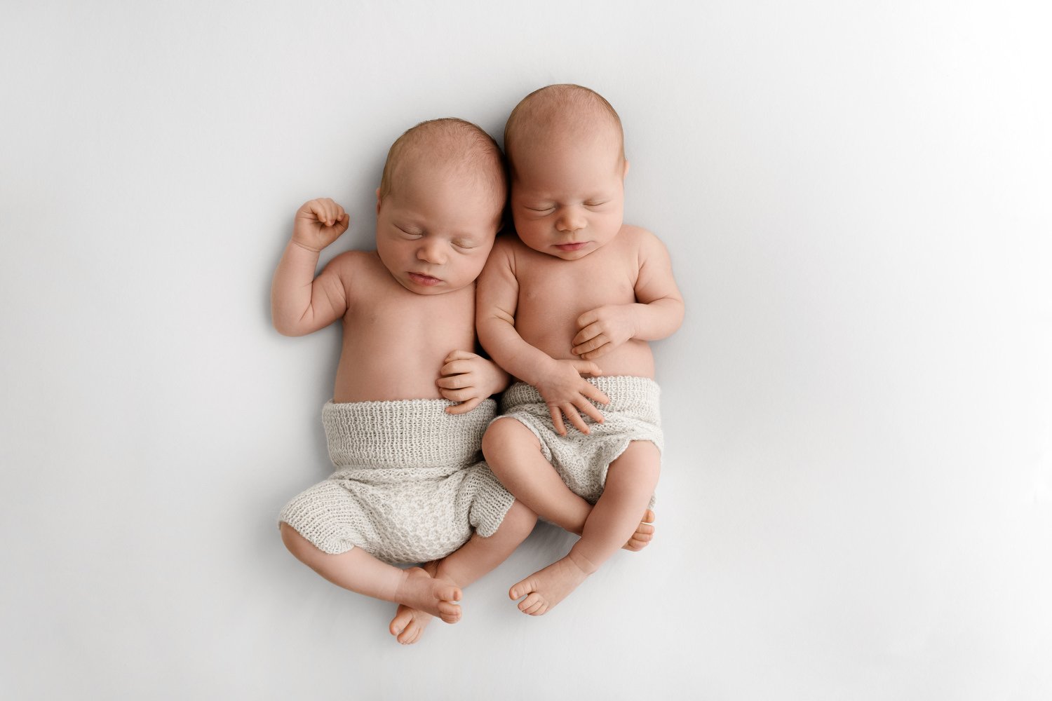 Newborn twin babies snuggling together natural photography Dundee wearing neutral knitted rompers