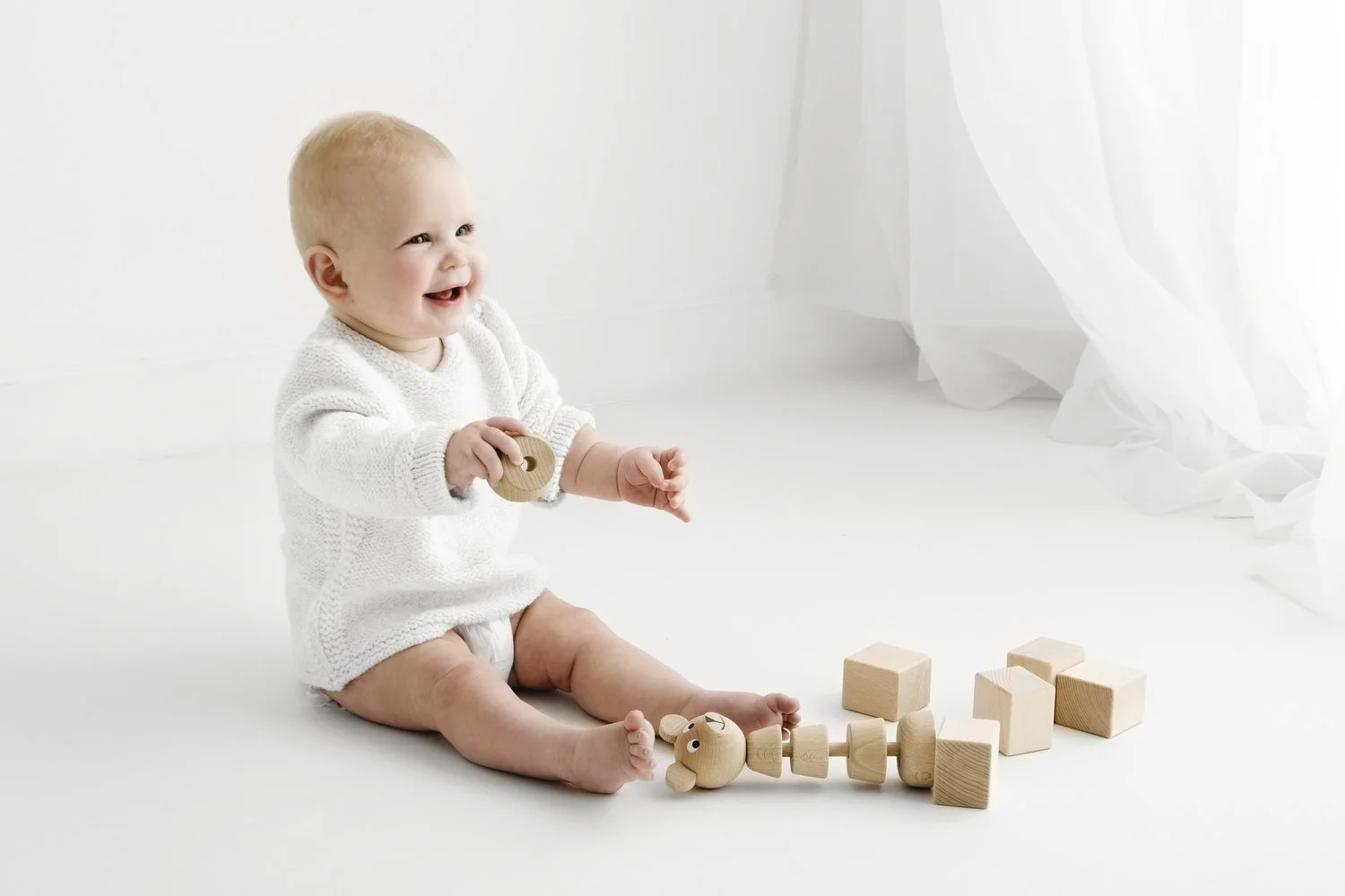 9 month old baby playing with wooden toy during studio photoshoot in Dundee