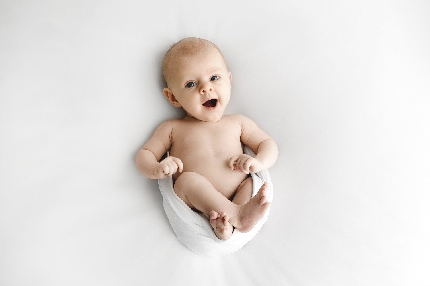 Smiling 8 week old baby curled up during Dundee studio photoshoot