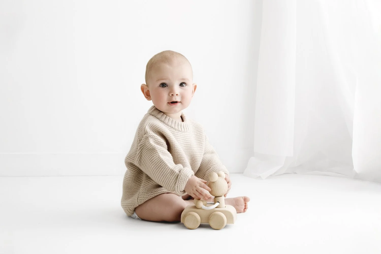 Sitting baby wearing neutral knitted jumper during Dundee studio photoshoot