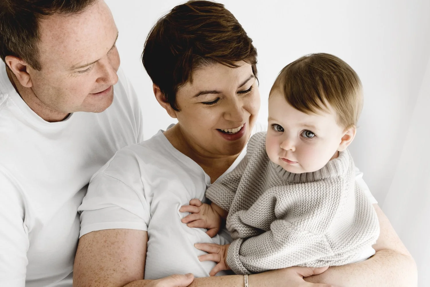 Nine month old baby with both parents during natural studio photoshoot in Dundee