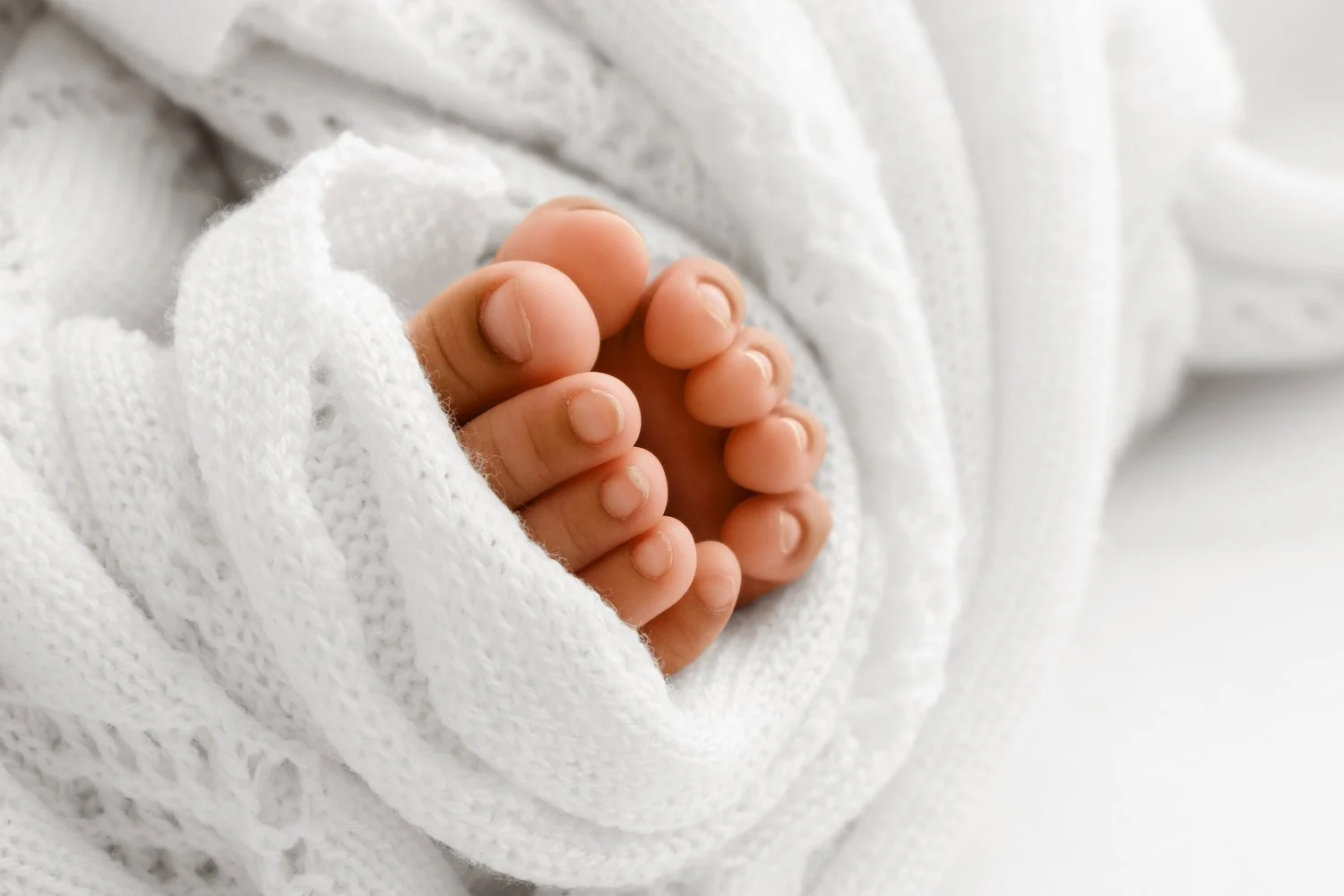 Close-up of three month old baby toes wrapped in soft white lace shawl during studio photoshoot in Dundee