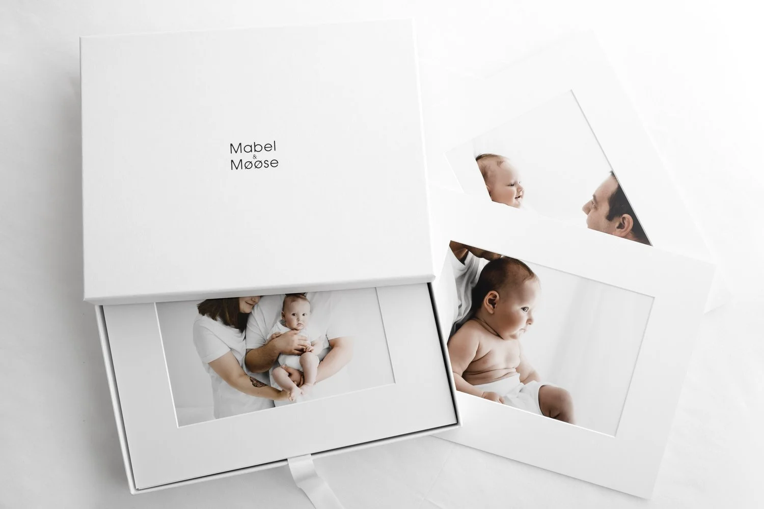 Mounted baby and parent photographs displayed in a Mabel & Møøse print collection box in Dundee studio