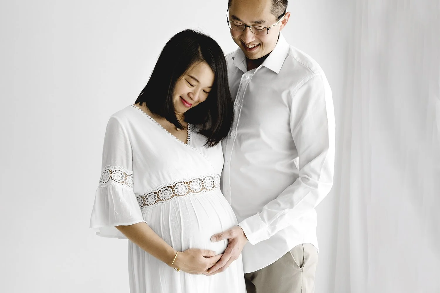 Pregnant couple in white clothing during relaxed maternity photoshoot at Dundee studio
