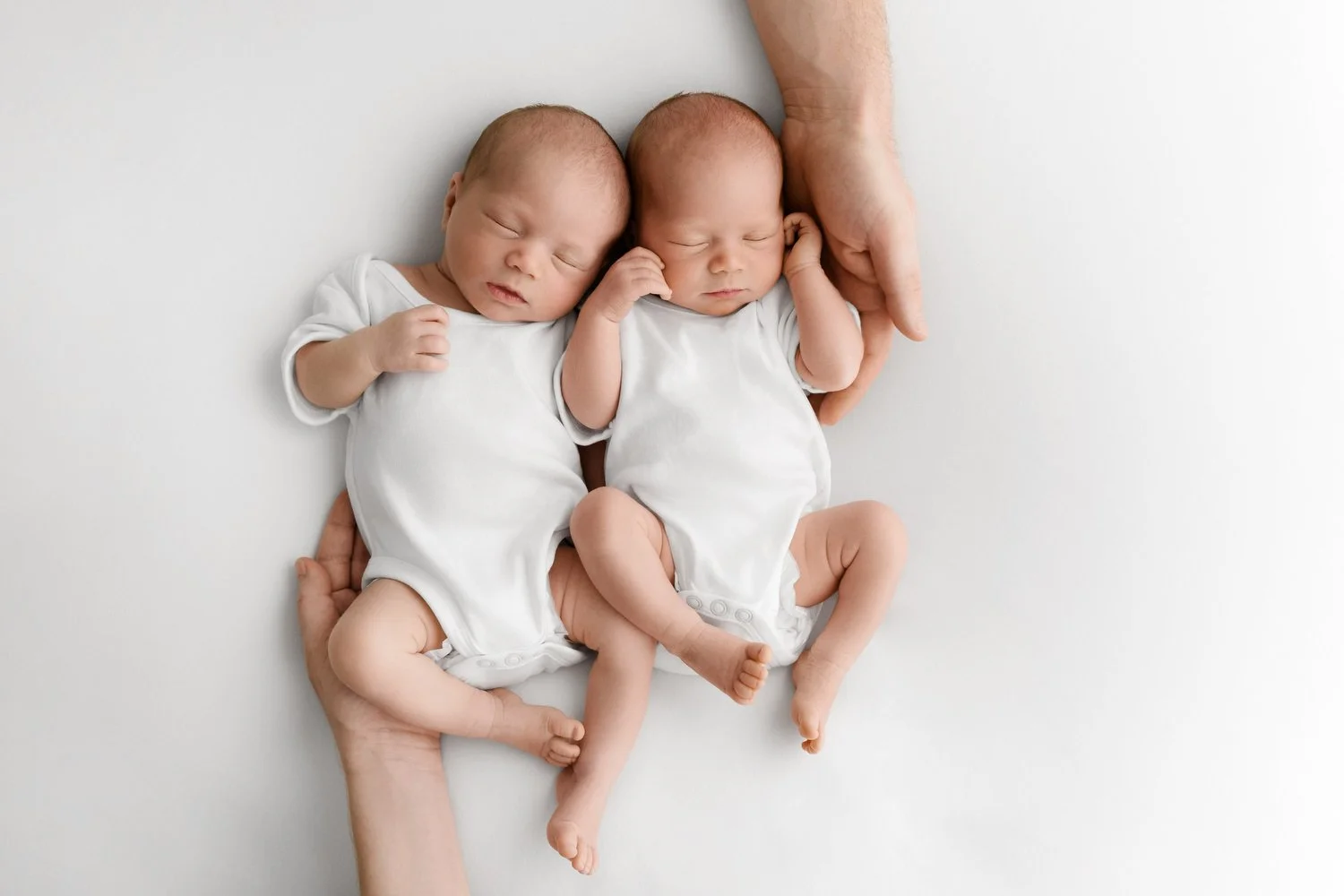 mum and dads hands holding Twin newborn babies photographed naturally at Mabel and Moose Dundee