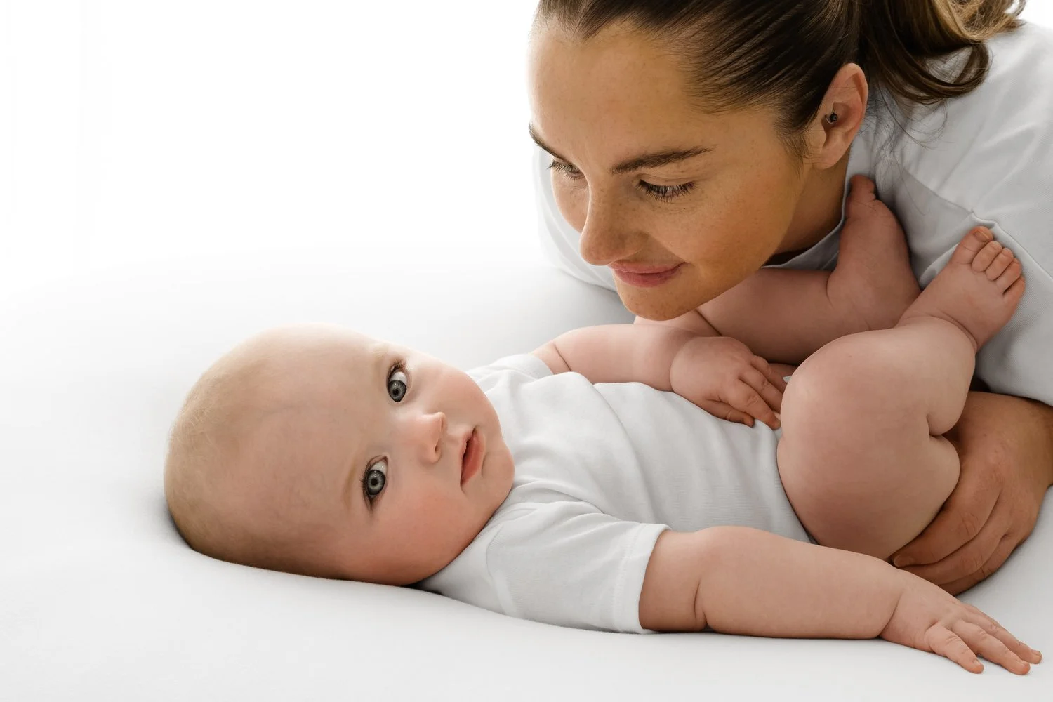 mum leaning over 6 month old baby photoshoot at Mabel and Moose studio Dundee